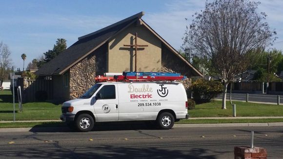 A double electric van is parked in front of a church