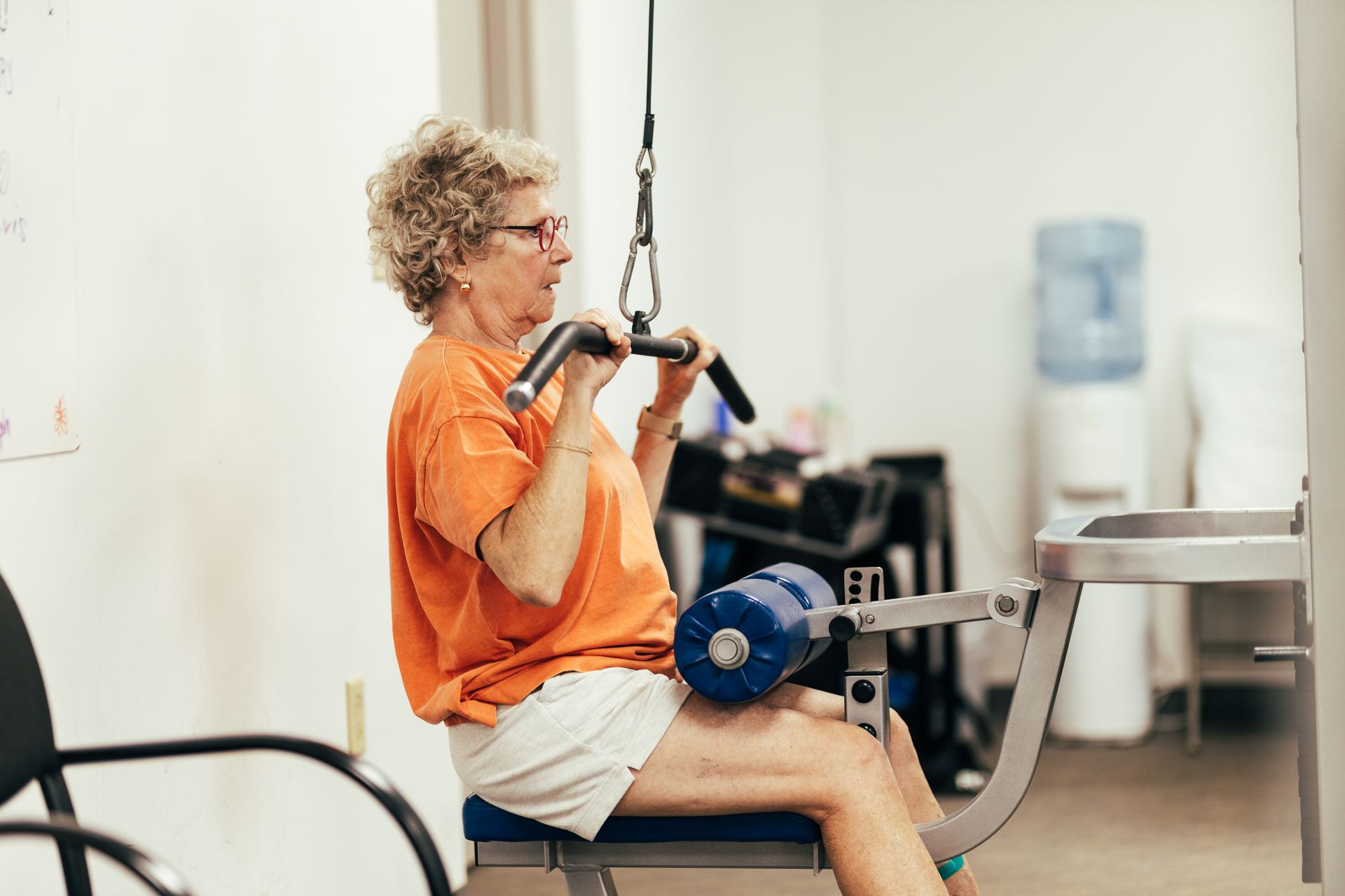 Woman using a lat pulldown machine at a gym, pulling down on the bar.