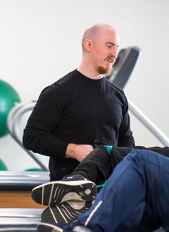 Man in blue plaid shirt smiles against a blue background.