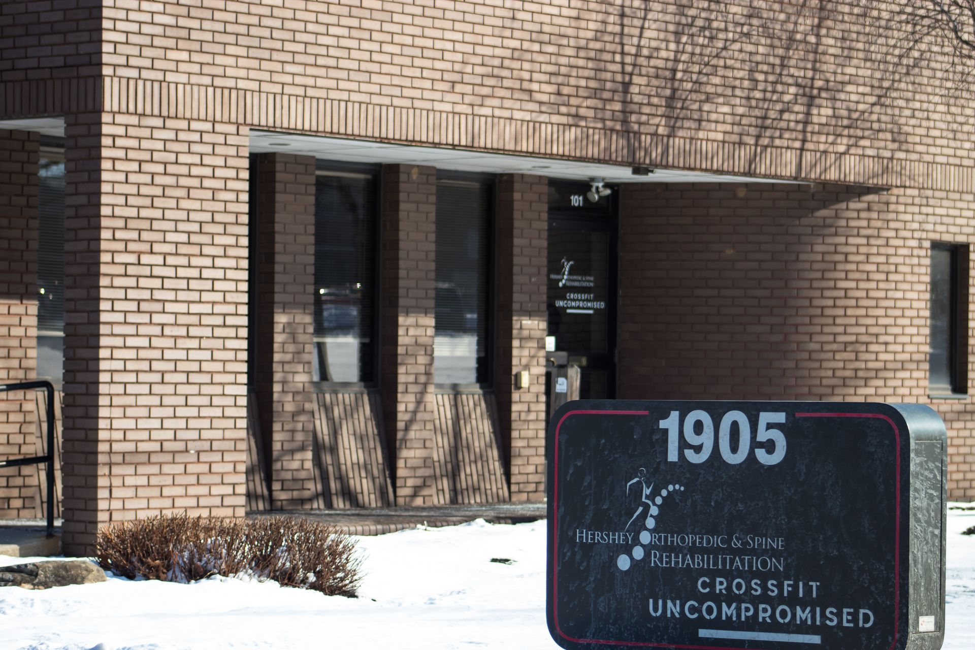 A brick building with a sign that says 1905 crossfit uncompromised