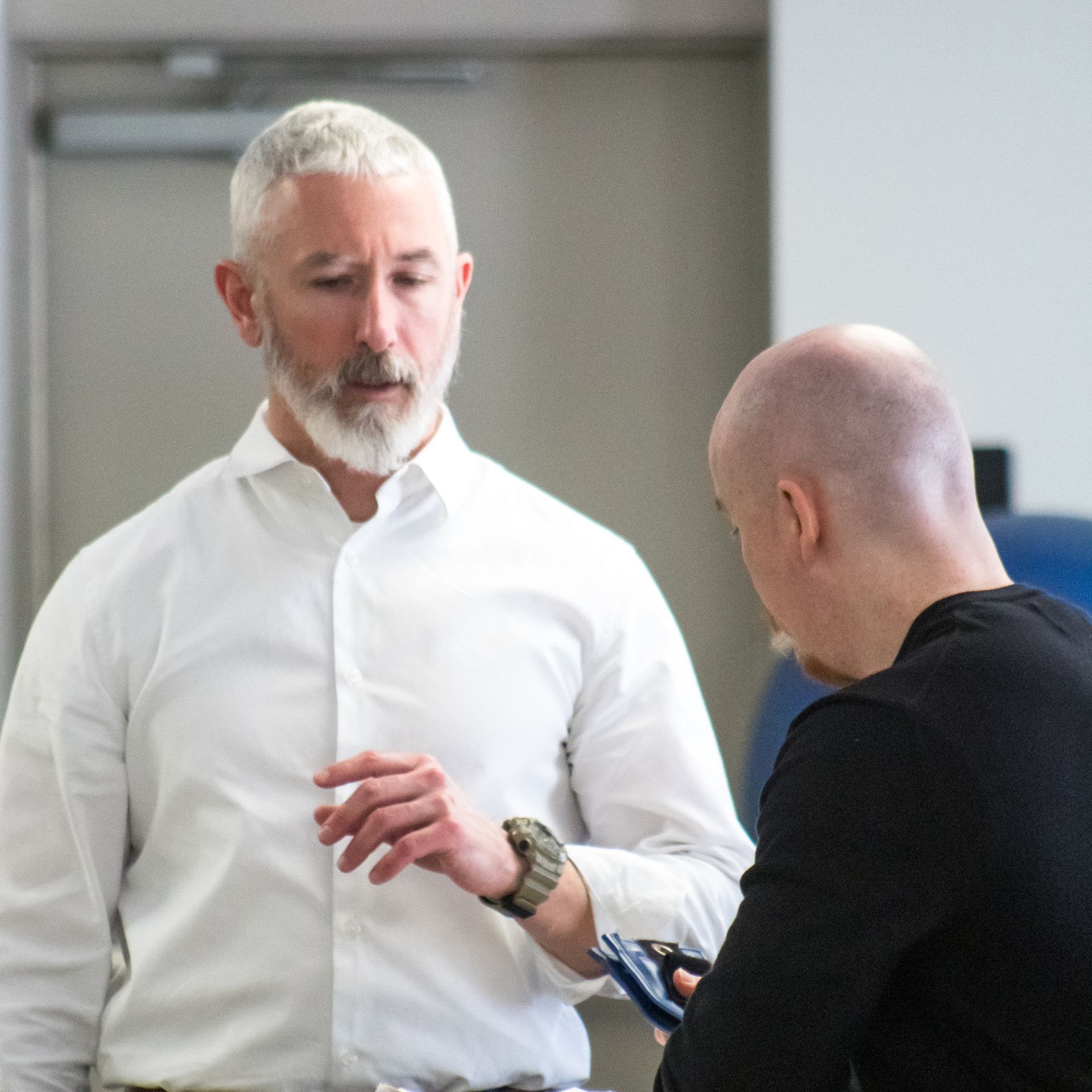 A man with a beard is talking to another man