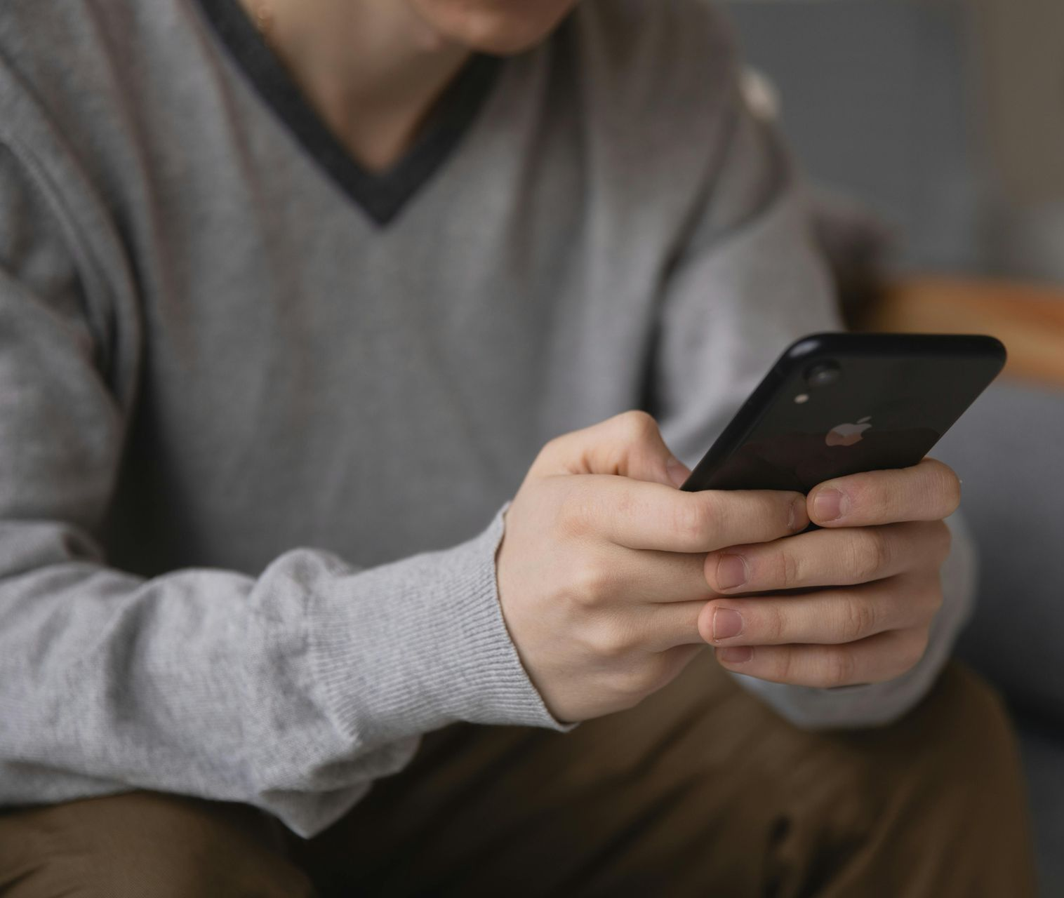Abstract figure using a phone. Sitting with legs crossed, blonde ponytail, geometric background, and warm colors.