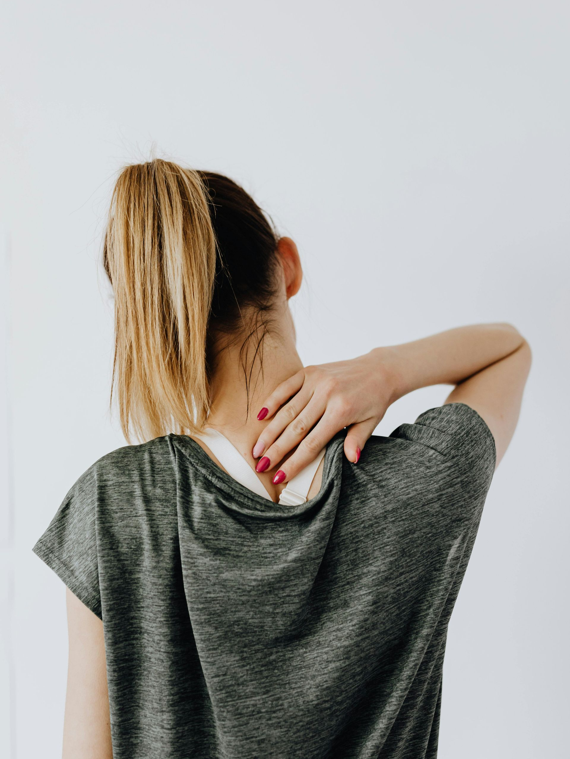 Abstract figure using a phone. Sitting with legs crossed, blonde ponytail, geometric background, and warm colors.