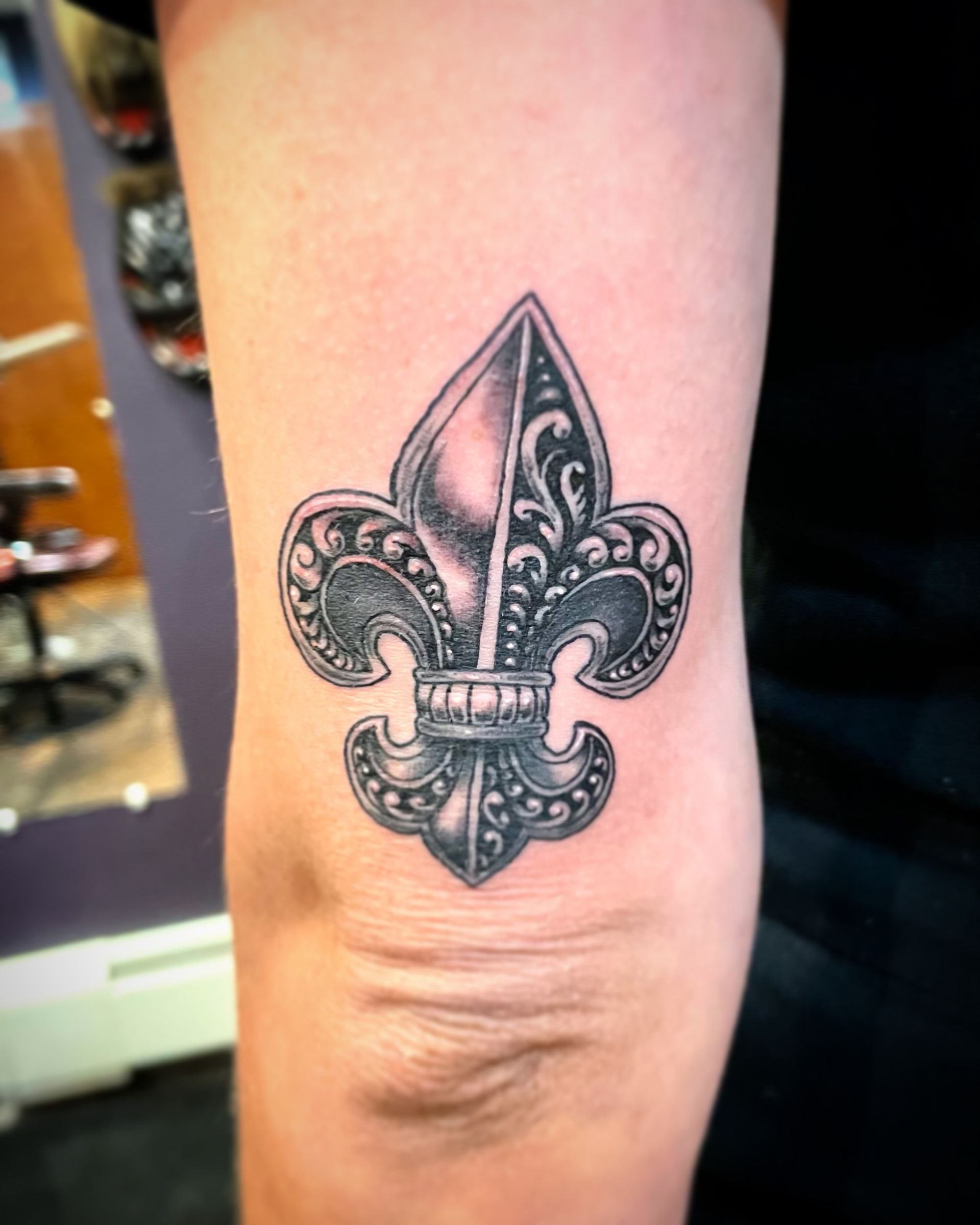  Intricate black fleur-de-lis tattoo on the arm. Custom black and grey realism done by a skilled artist in Raleigh, NC.