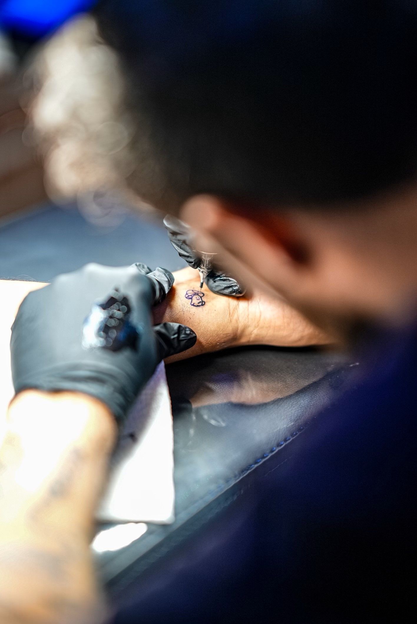 Tattoo artist creating a fine line black ink design at TEETS X Aether flash tattoo event in Raleigh, NC.