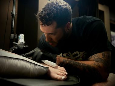 Cameron Tattooing: Apprentice at Aether Tattoo in Raleigh, NC, Tattoo artist creating a foot tattoo, focused workspace scene