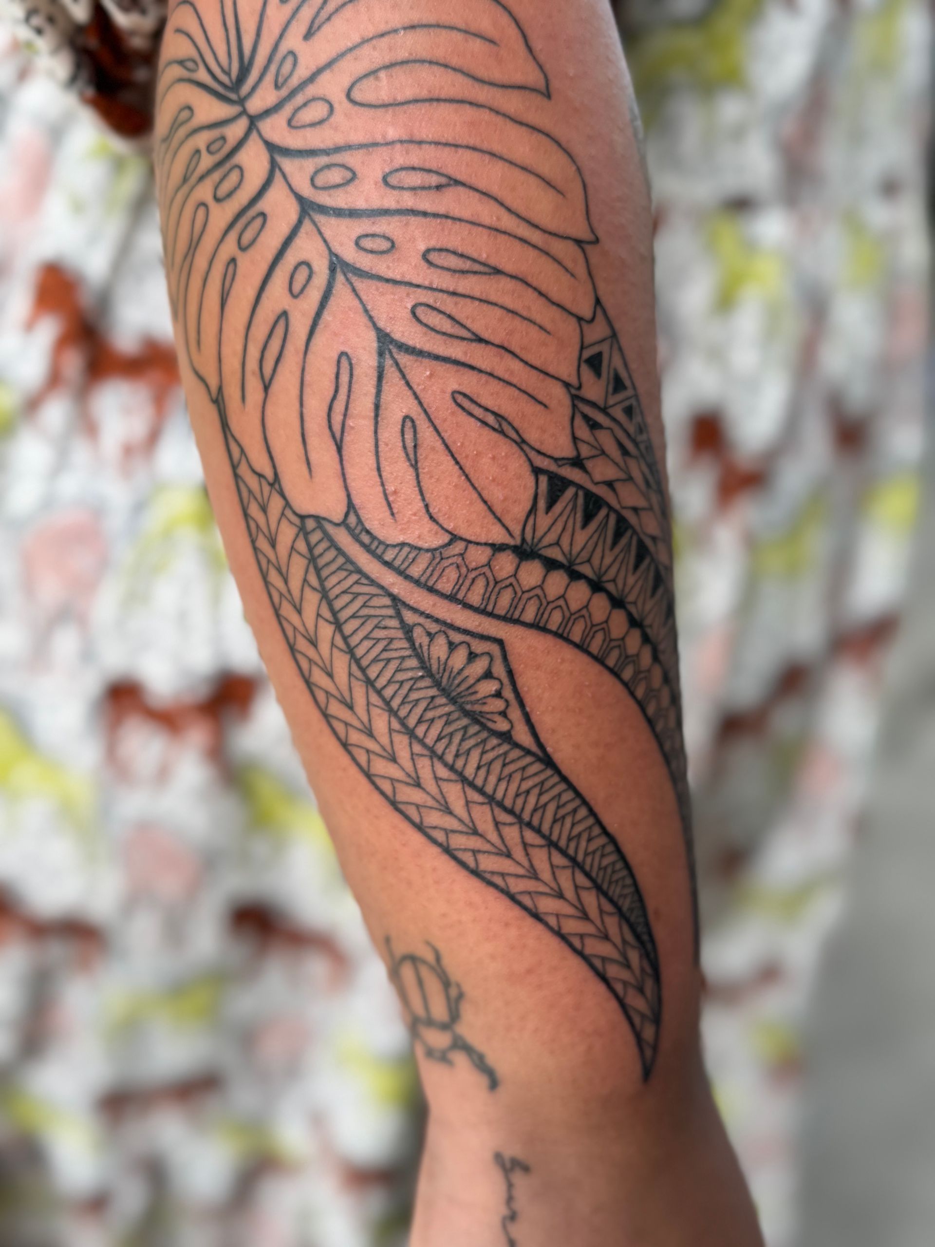 A person has a tattoo of a leaf on their arm