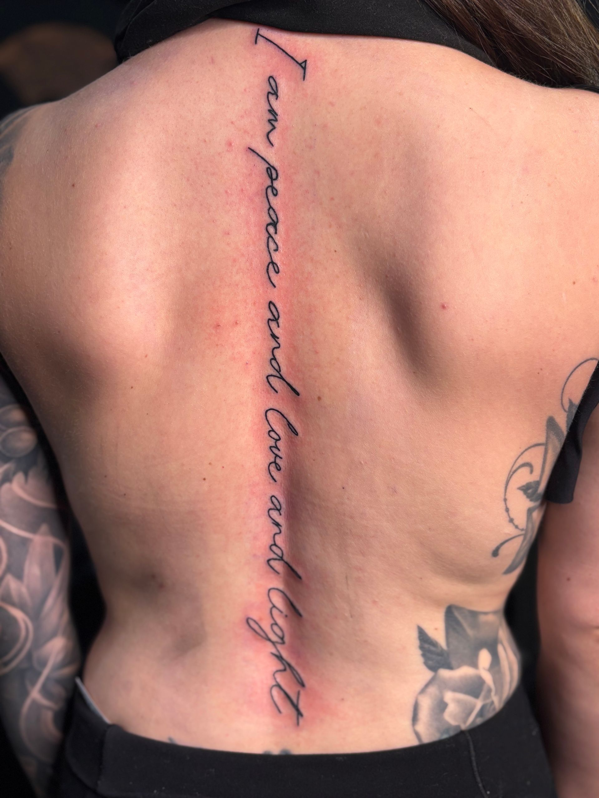 Back tattoo: vertical script reads