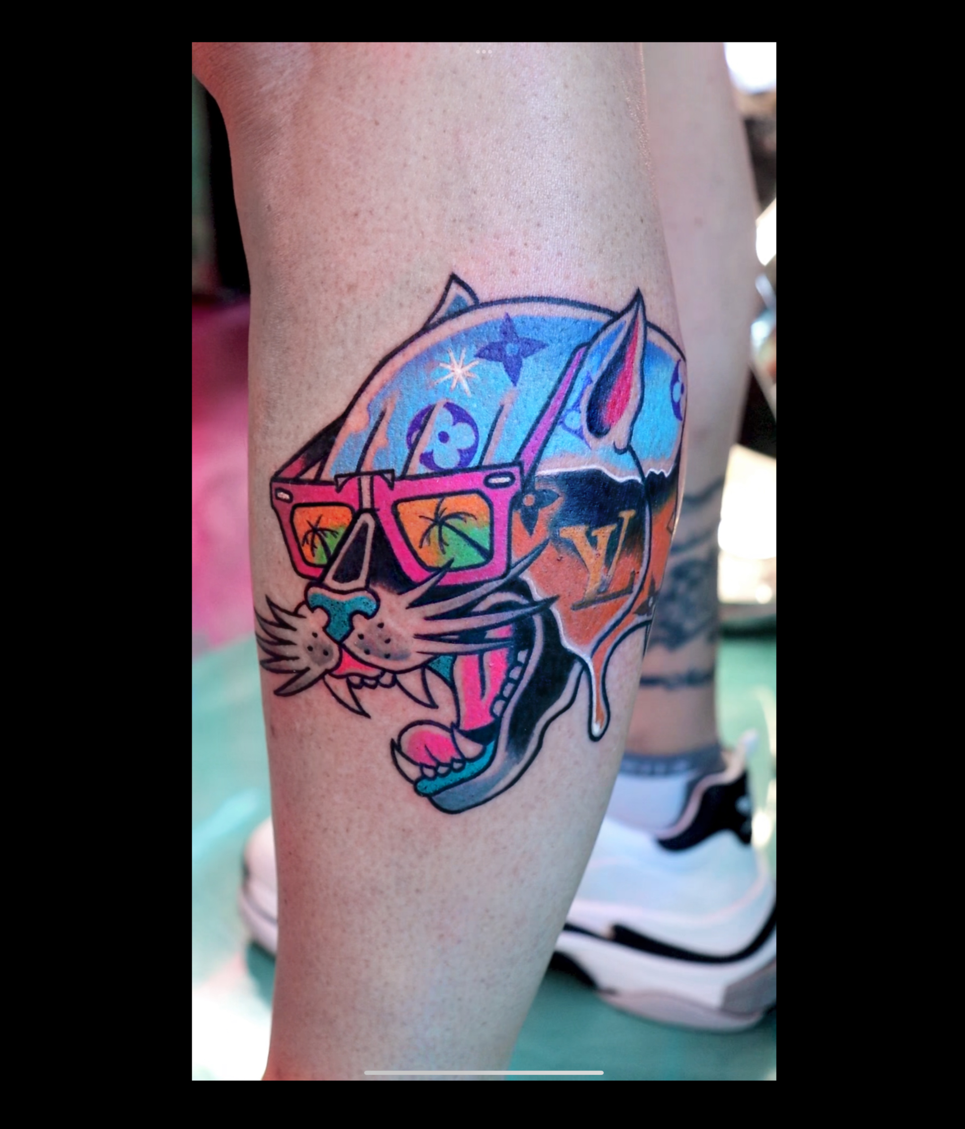 A colorful tattoo of a cat wearing sunglasses