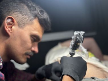 Vanité, Female tattoo artist working on a client, close-up of arm tattoo.