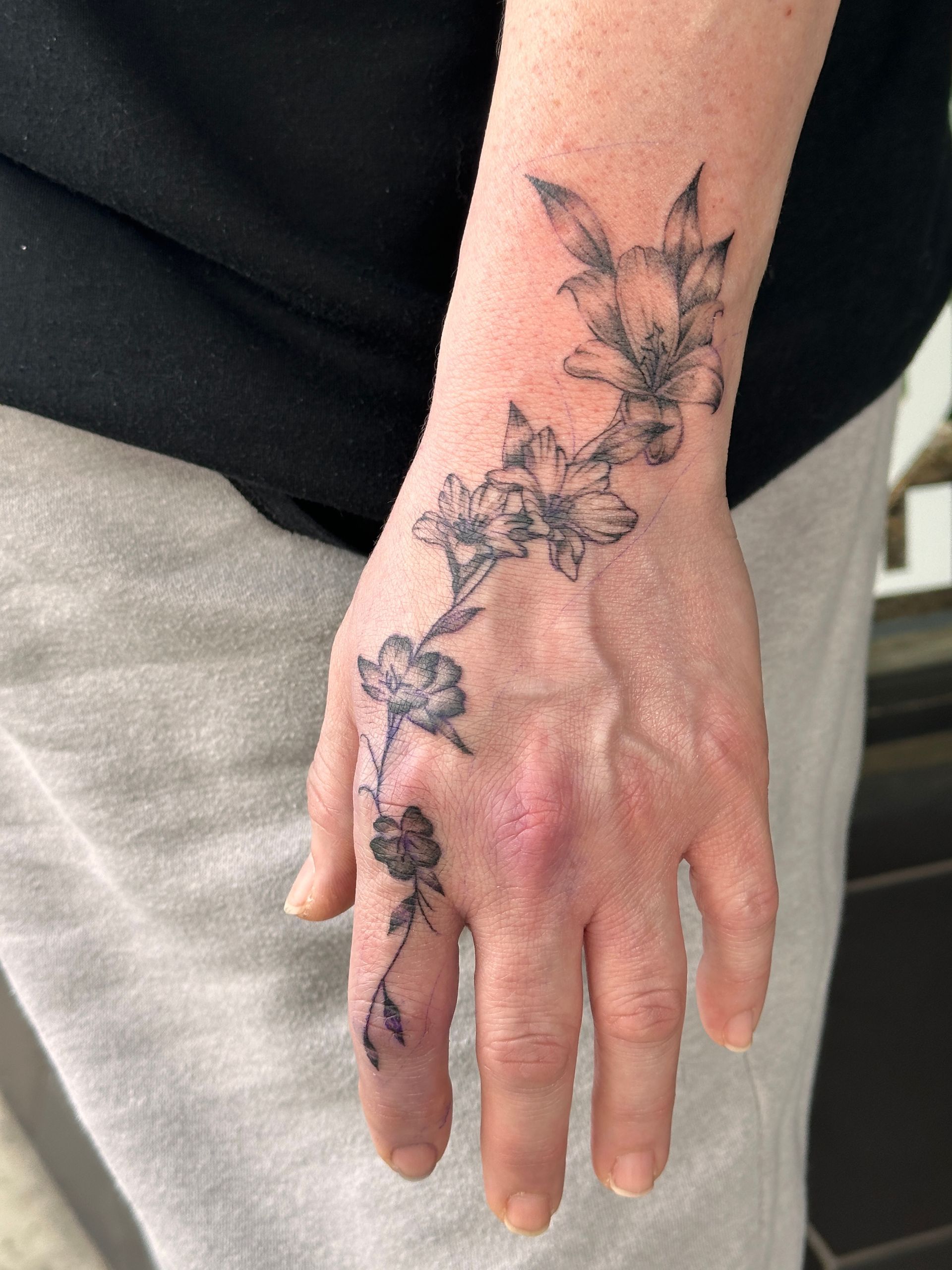 A woman has a tattoo of flowers on her hand.