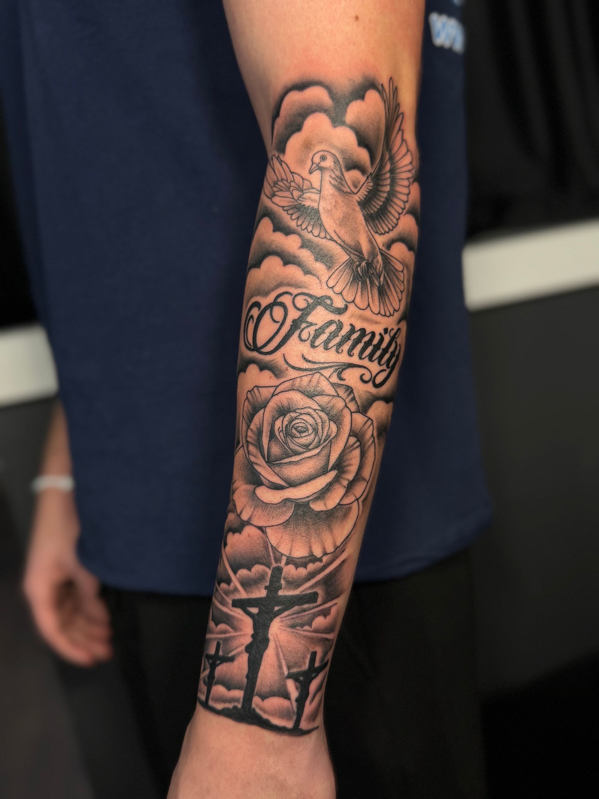 black and grey half sleeve of Jesus, three crosses, a rose, a dove, and family