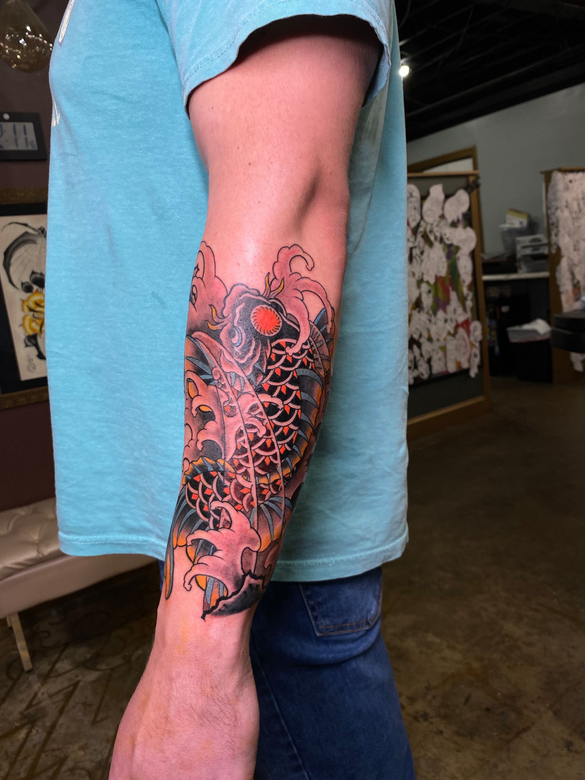 Colorful koi fish tattoo on arm at one of the best tattoo parlors in Raleigh, NC. Custom Japanese tattoo with vibrant colors.