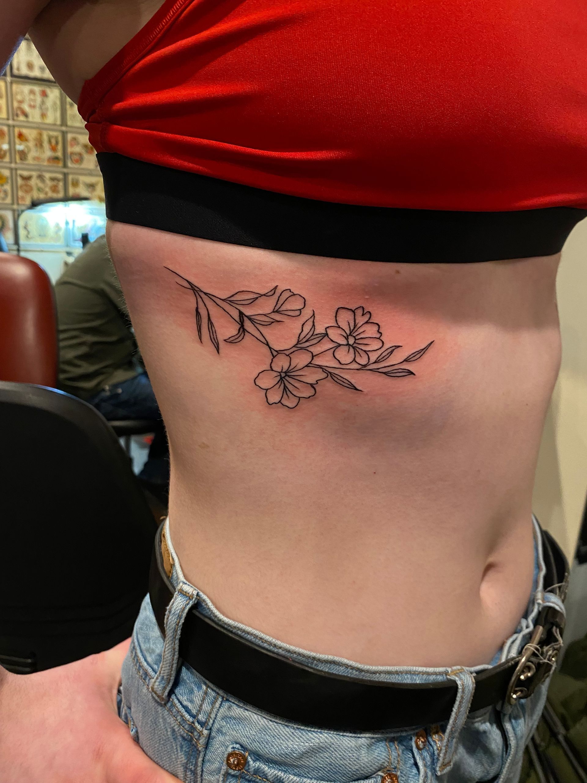 Fine line floral tattoo on ribs, custom blackwork design in Raleigh.