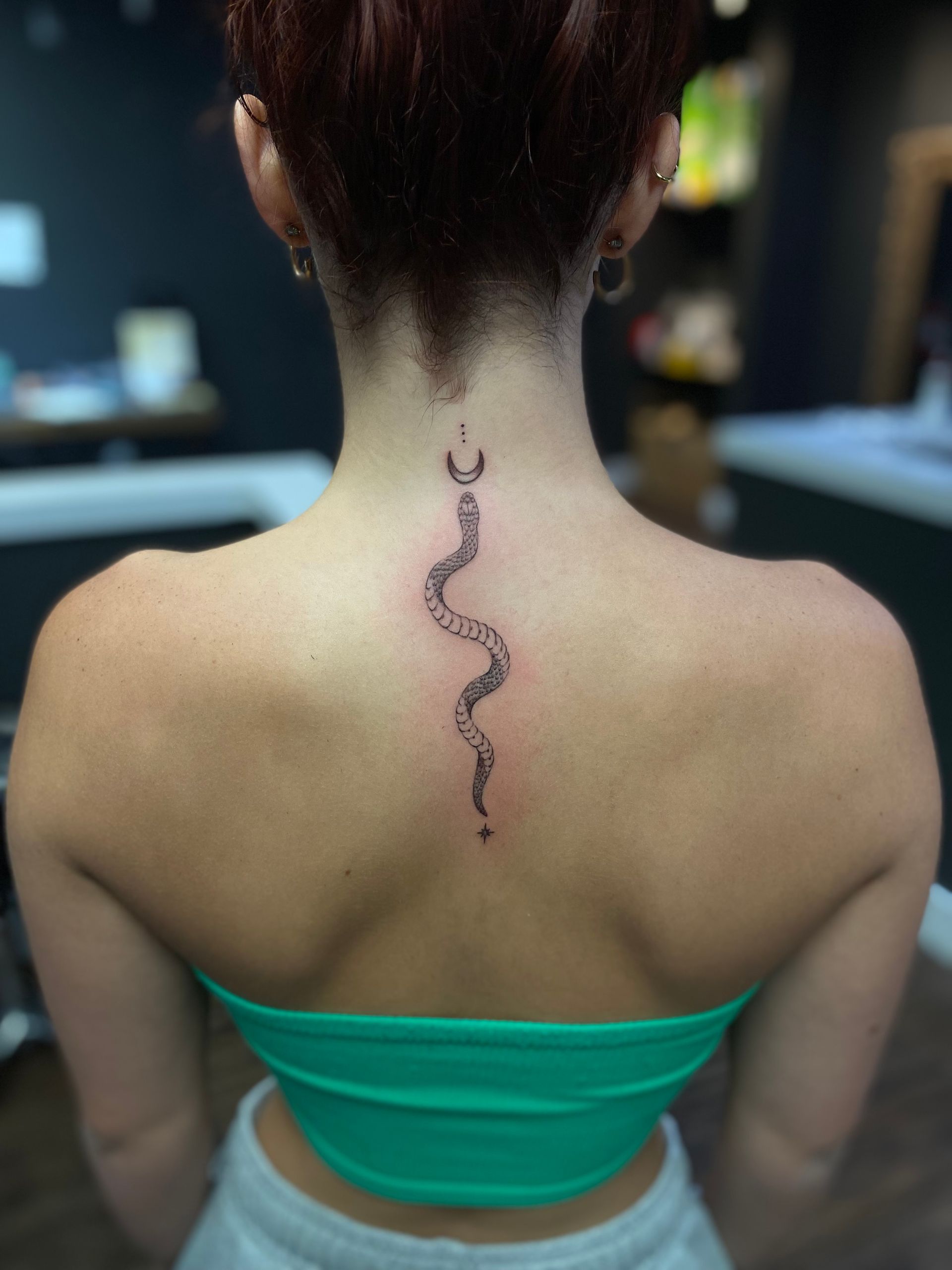 Snake and crescent moon tattoo on the back of the neck, designed by one of the top tattoo artists Raleigh. Walk-ins welcome.