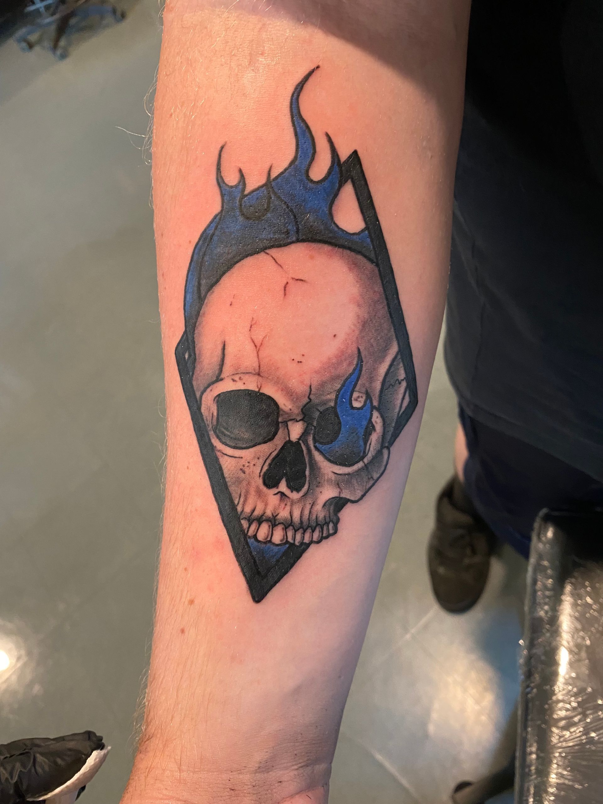 Black and blue skull with flames tattoo on the forearm. A bold piece done at a walk-in tattoo shop in Raleigh, NC.