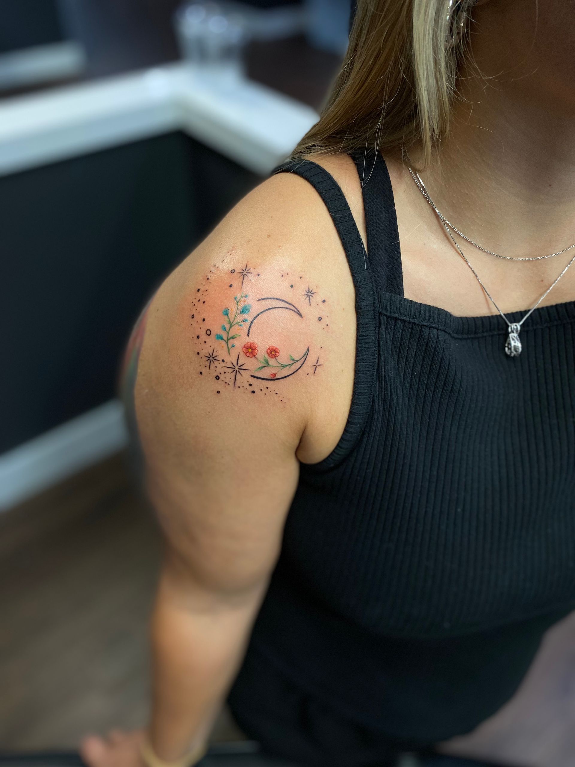 Colored crescent moon with flowers on shoulder, custom tattoo design in Raleigh.