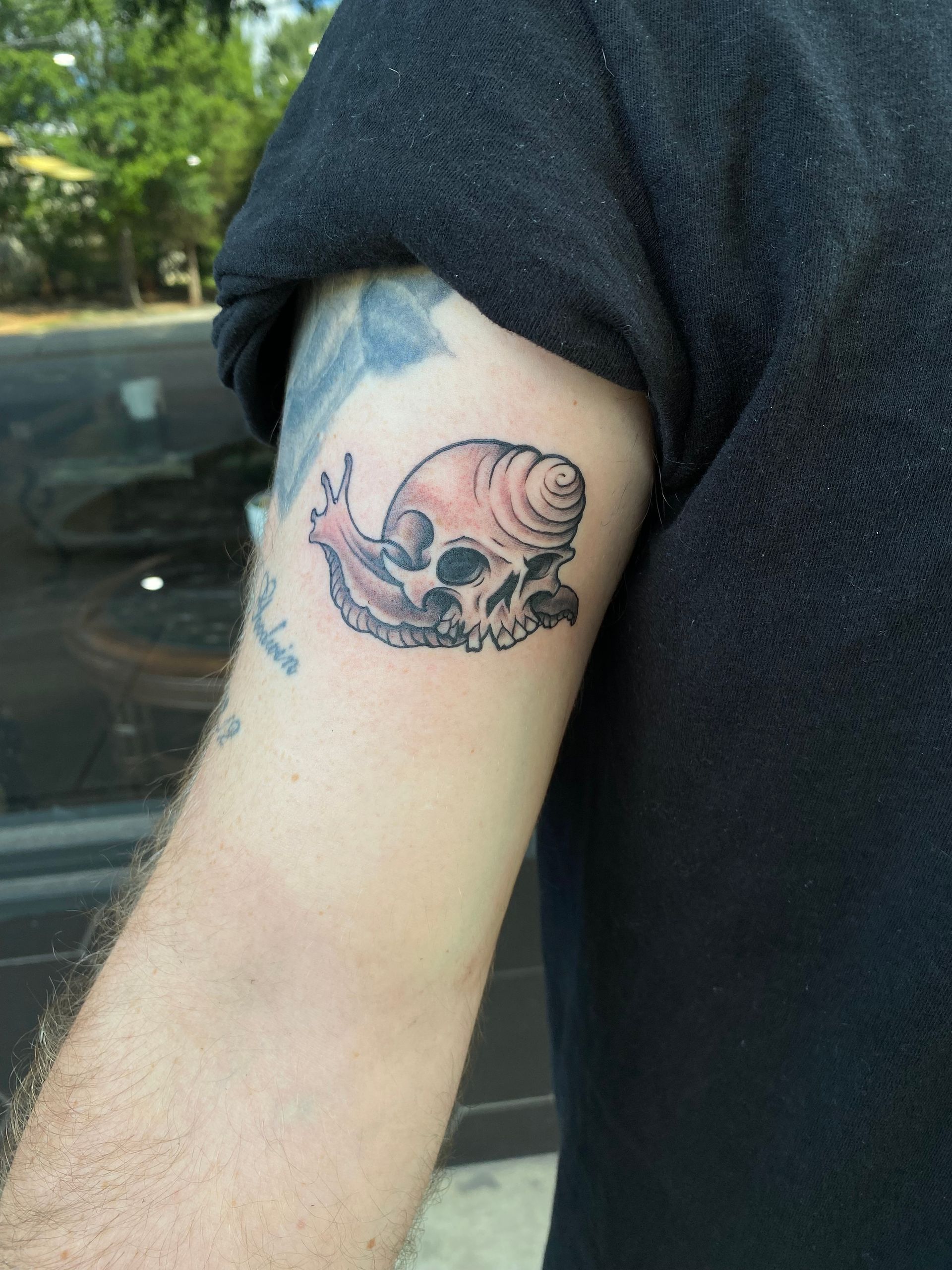 Snail shell fused with skull tattoo on arm, custom realism work in Raleigh.