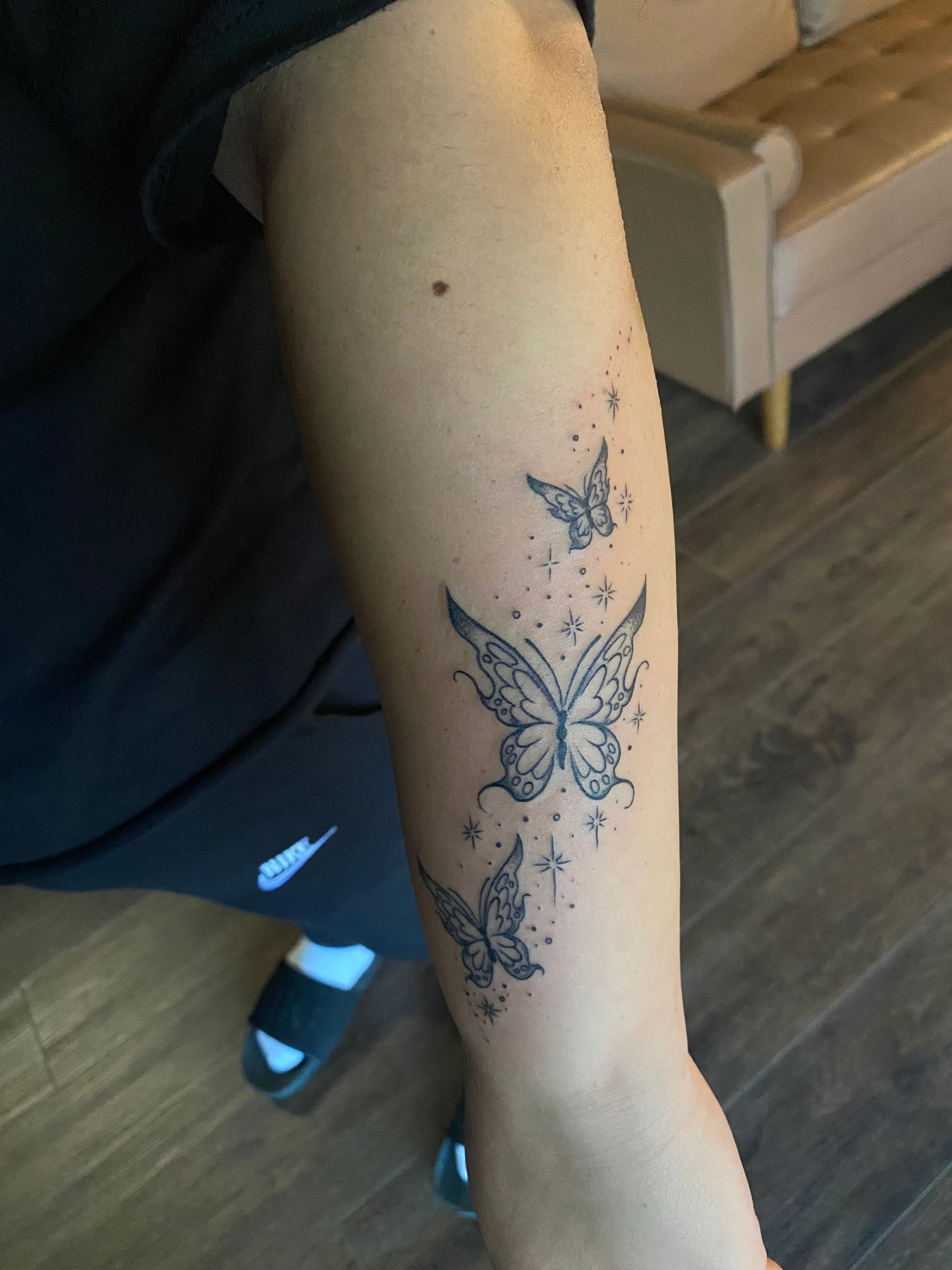 Black and grey butterfly forearm tattoo with sparkles, fine line style in Raleigh.