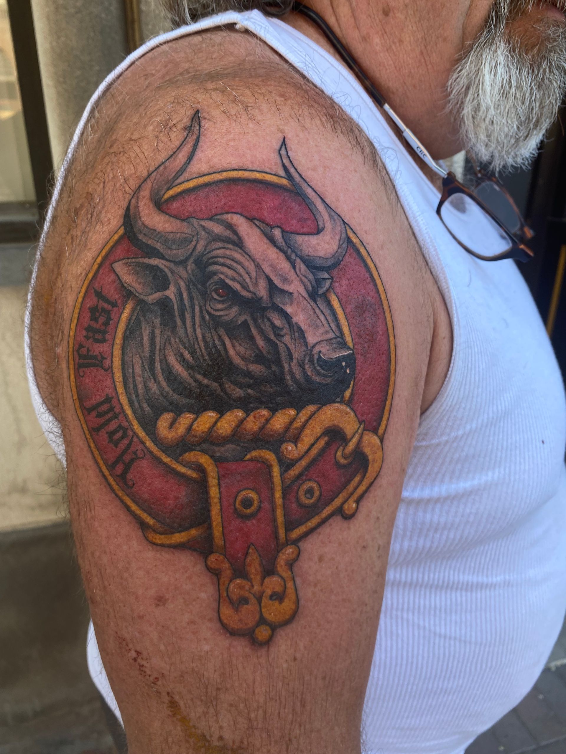 Realistic black and red bull head tattoo on upper arm, done by a top tattoo artist in Raleigh NC at a premier tattoo parlor.