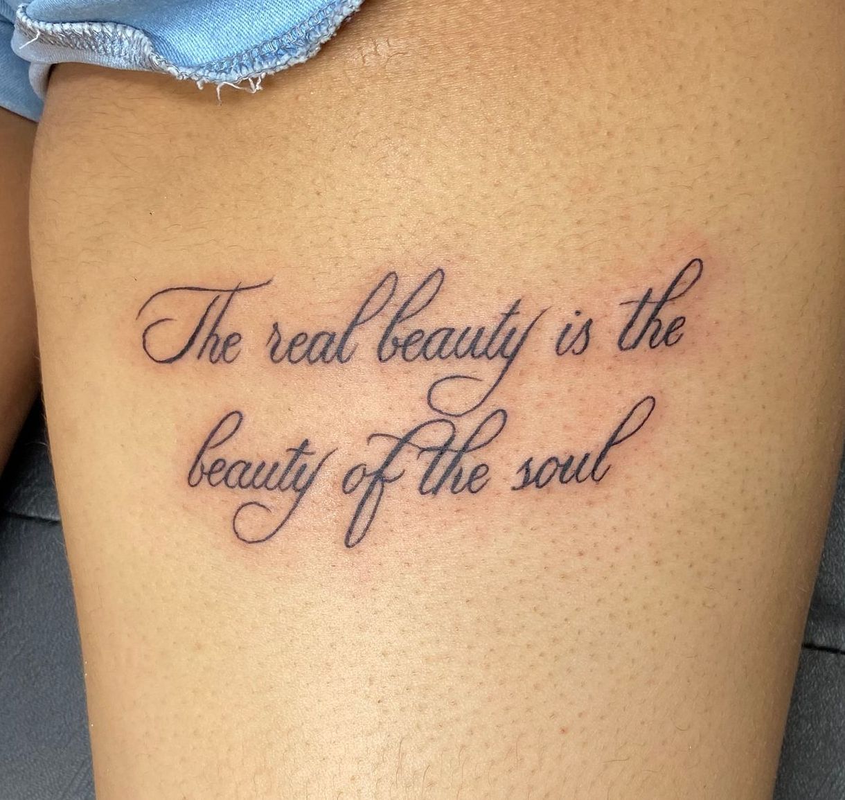 Thigh script tattoo, 'The real beauty is the beauty of the soul,' in Raleigh.