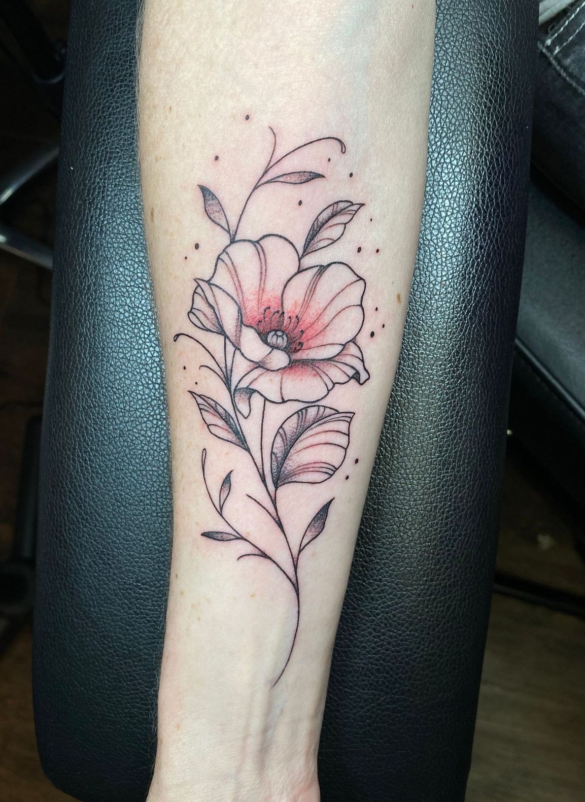 “Floral tattoo on forearm, pink shading with soft black lines.