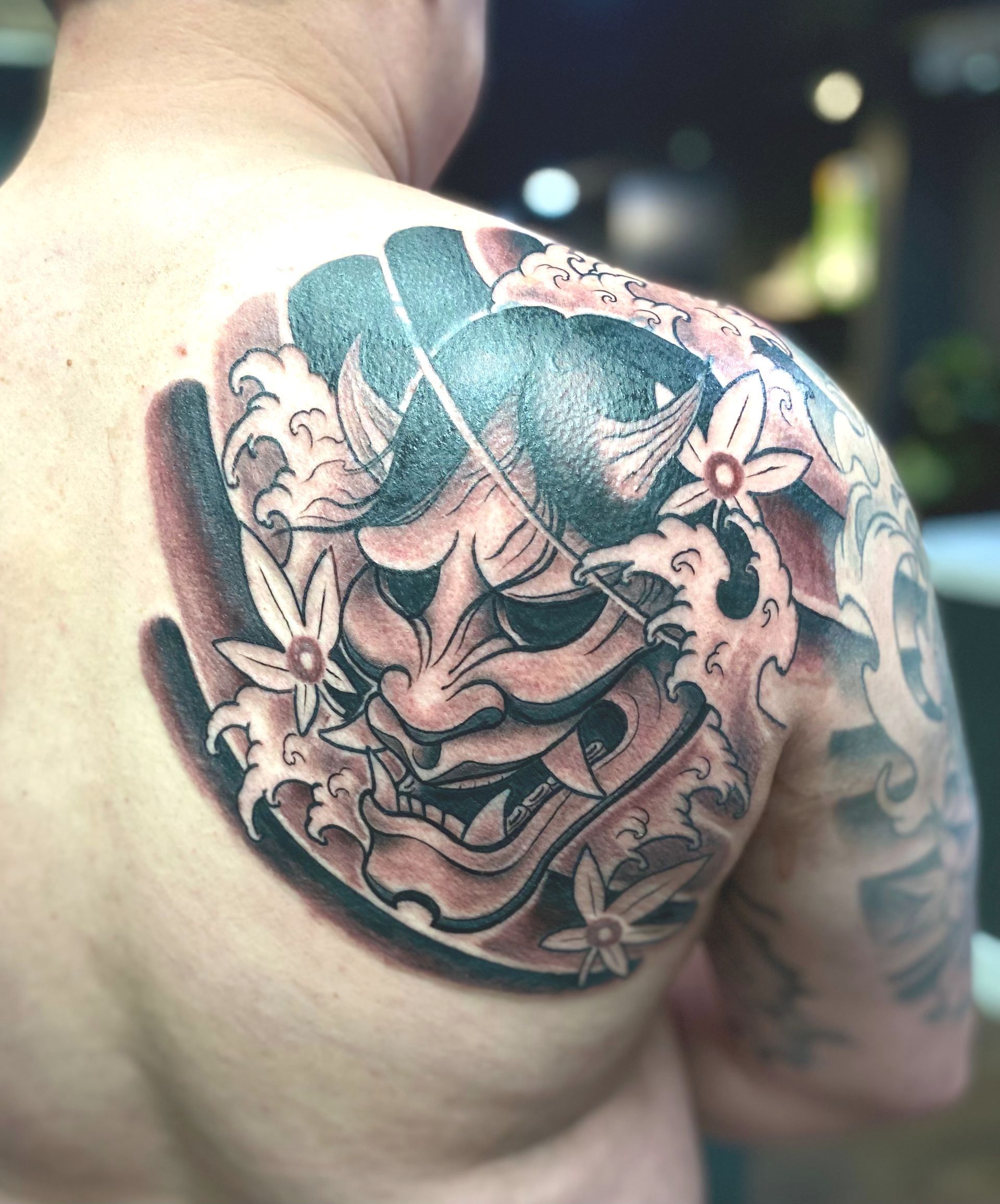 Black and grey Japanese Oni mask tattoo by a tattoo artist near Hillsborough Street, Raleigh NC. Custom Japanese design.