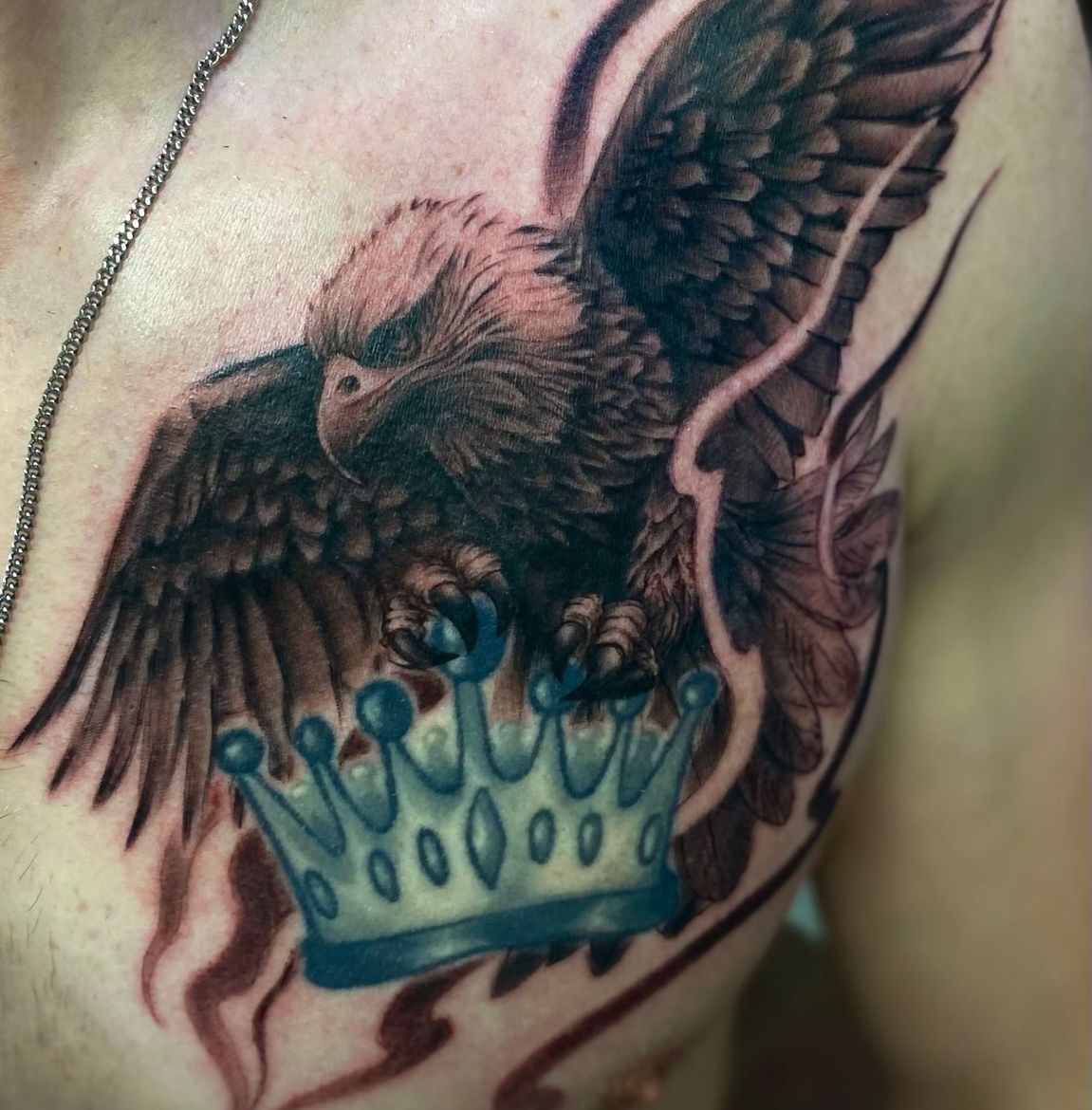 Black and grey eagle chest tattoo with crown, bold realism.