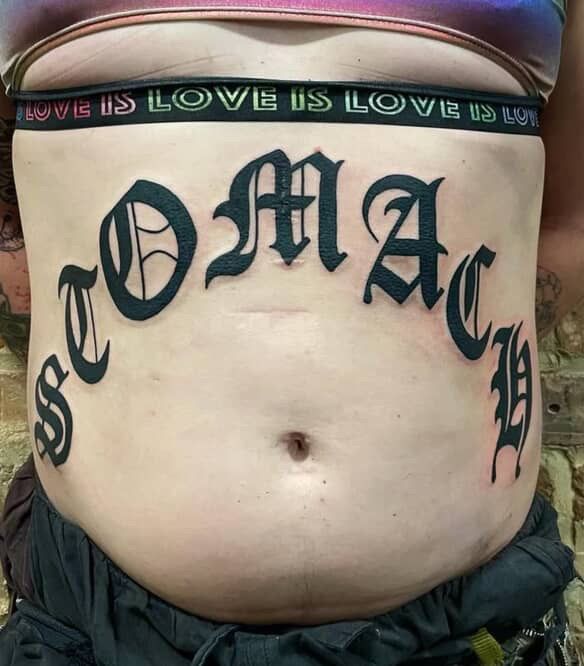 Belly tattoo: black gothic font spells