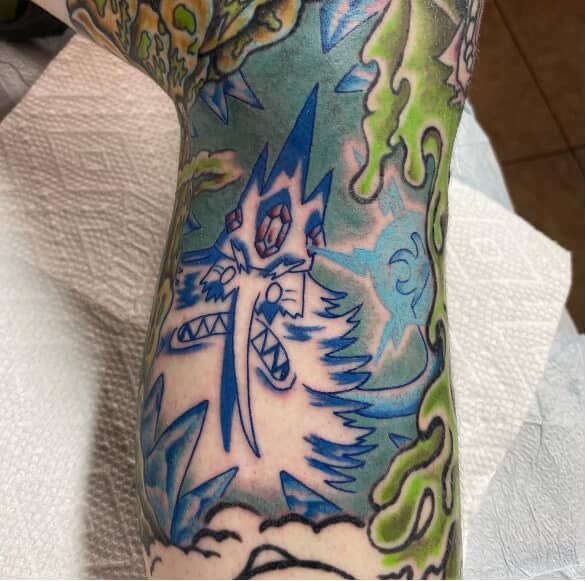 Tattoo of the Ice King from Adventure Time, blue and white, with green slime and blue lightning on a leg.