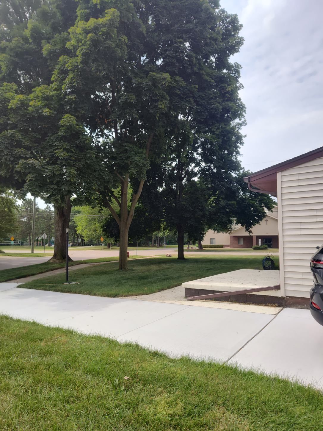 A car is parked in front of a house with trees in the background
