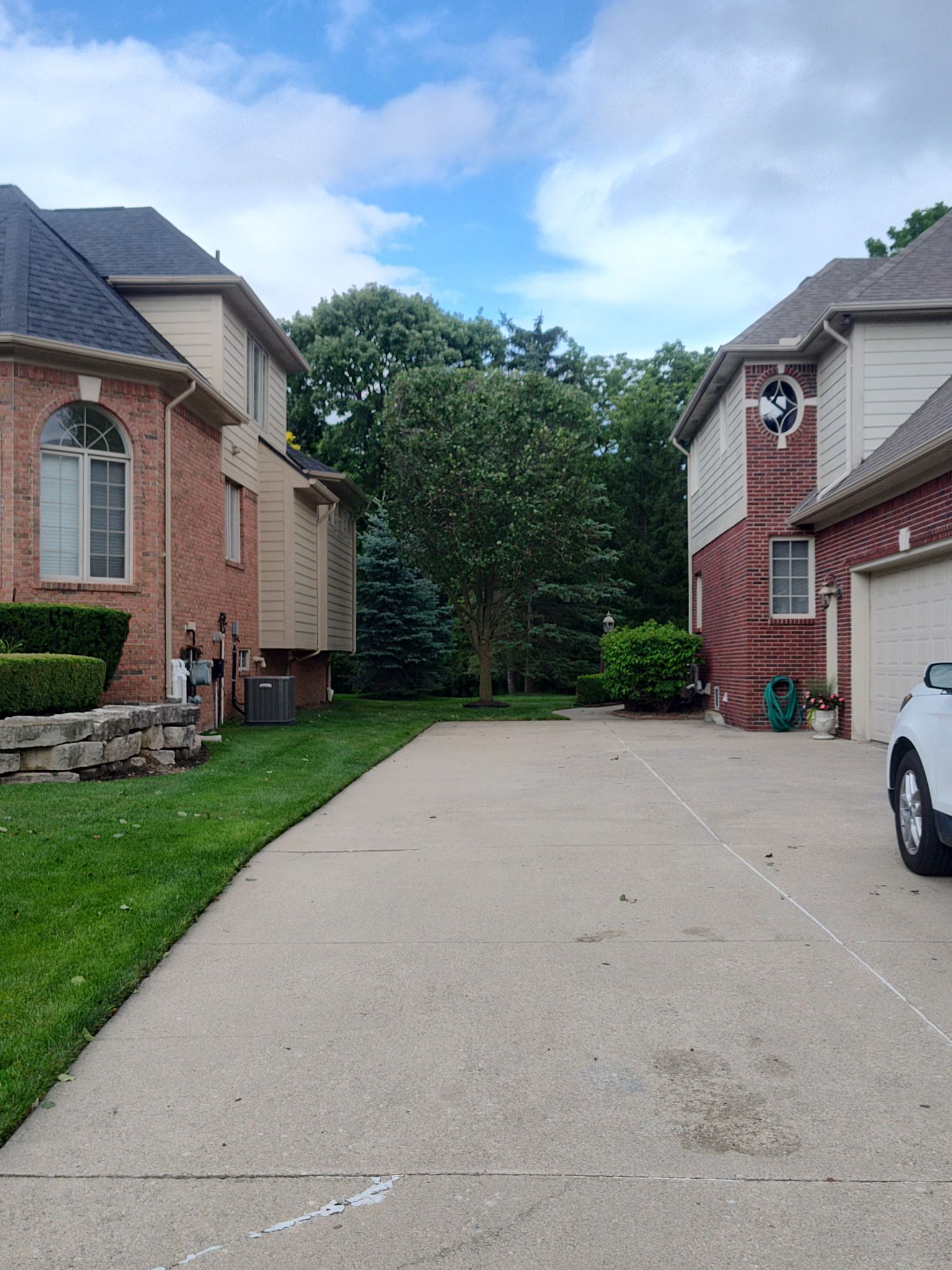 A white car is parked in front of a brick house