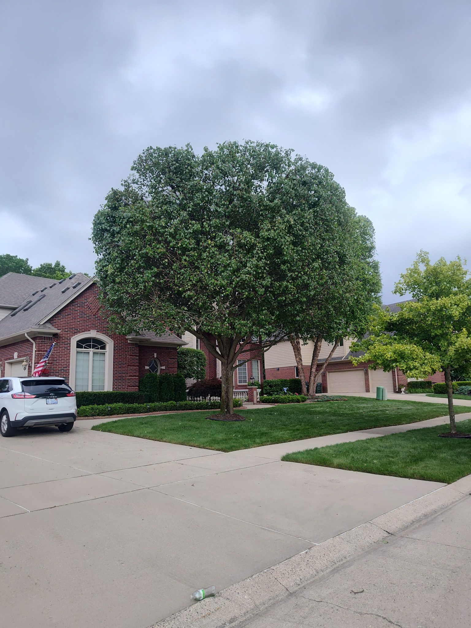 A white car is parked in front of a brick house.
