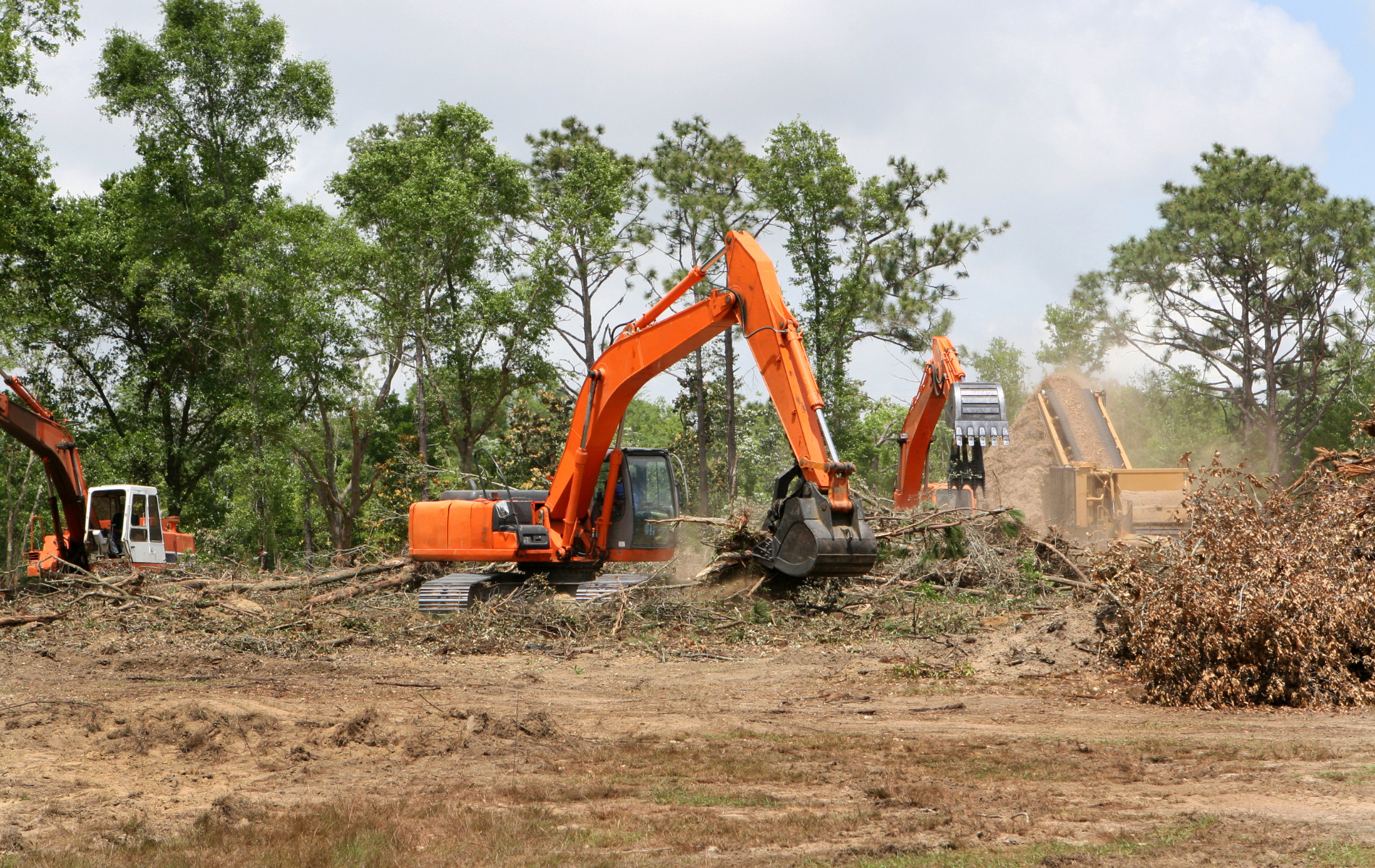 A couple of excavators are working on a dirt field.