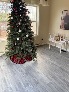 Christmas tree decorated with red and white ornaments, in a room with light gray flooring.