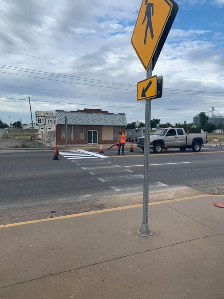 A man is painting a crosswalk sign on the side of the road