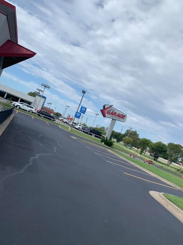 A car is parked in a parking lot in front of a burger king restaurant.