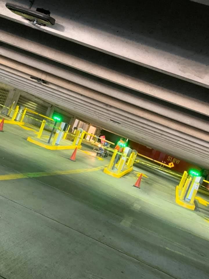 A parking garage with yellow cones and green lights.