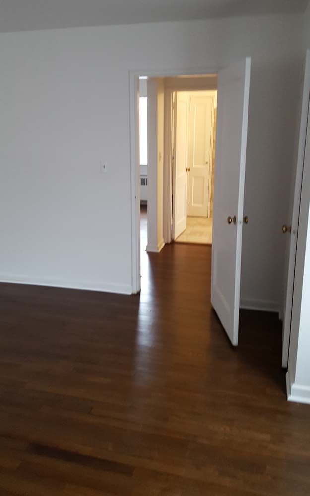 An empty bedroom with hardwood floors and a closet.
