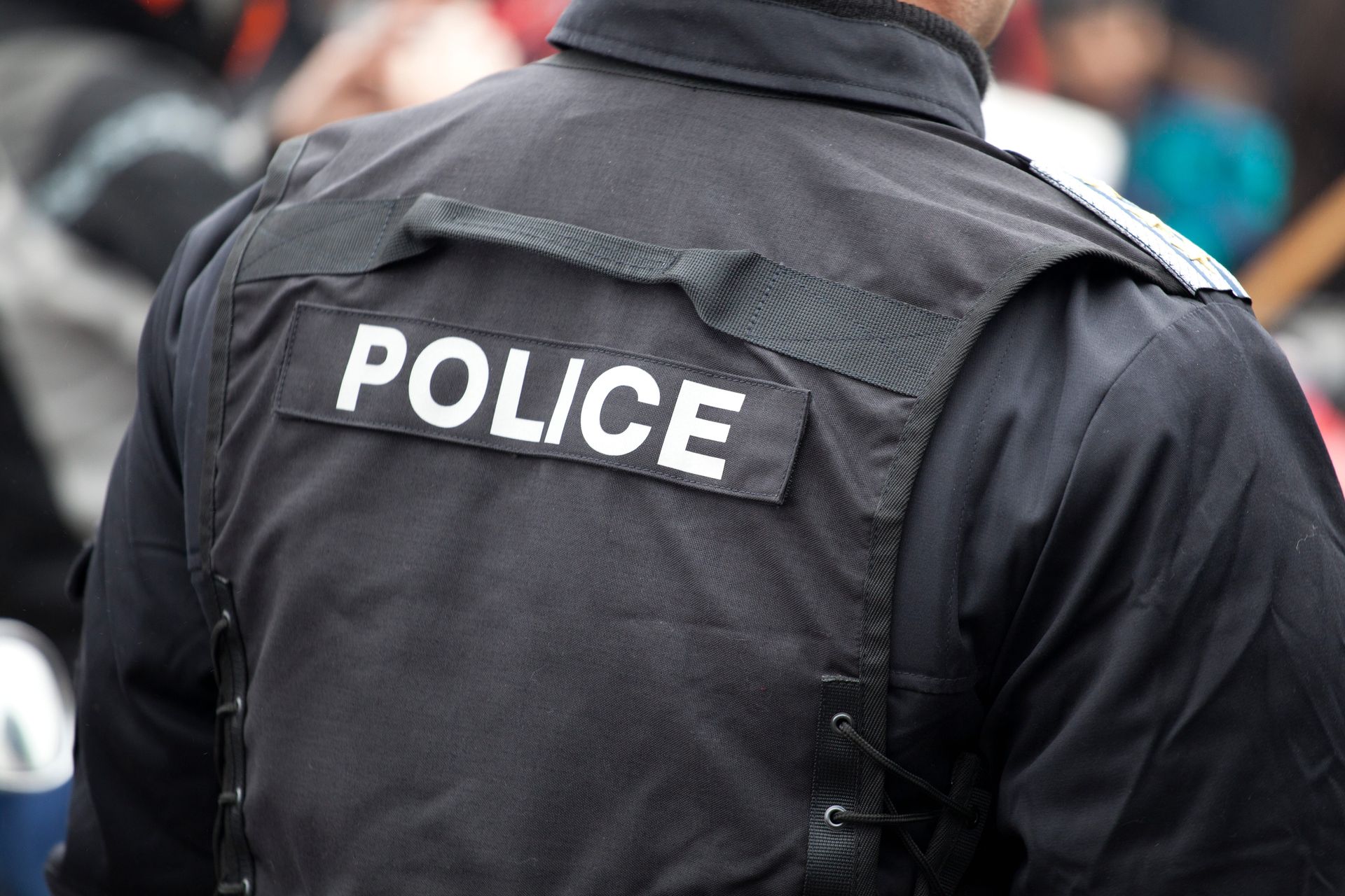 Back of a police officer wearing a black jacket with “POLICE” in white letters