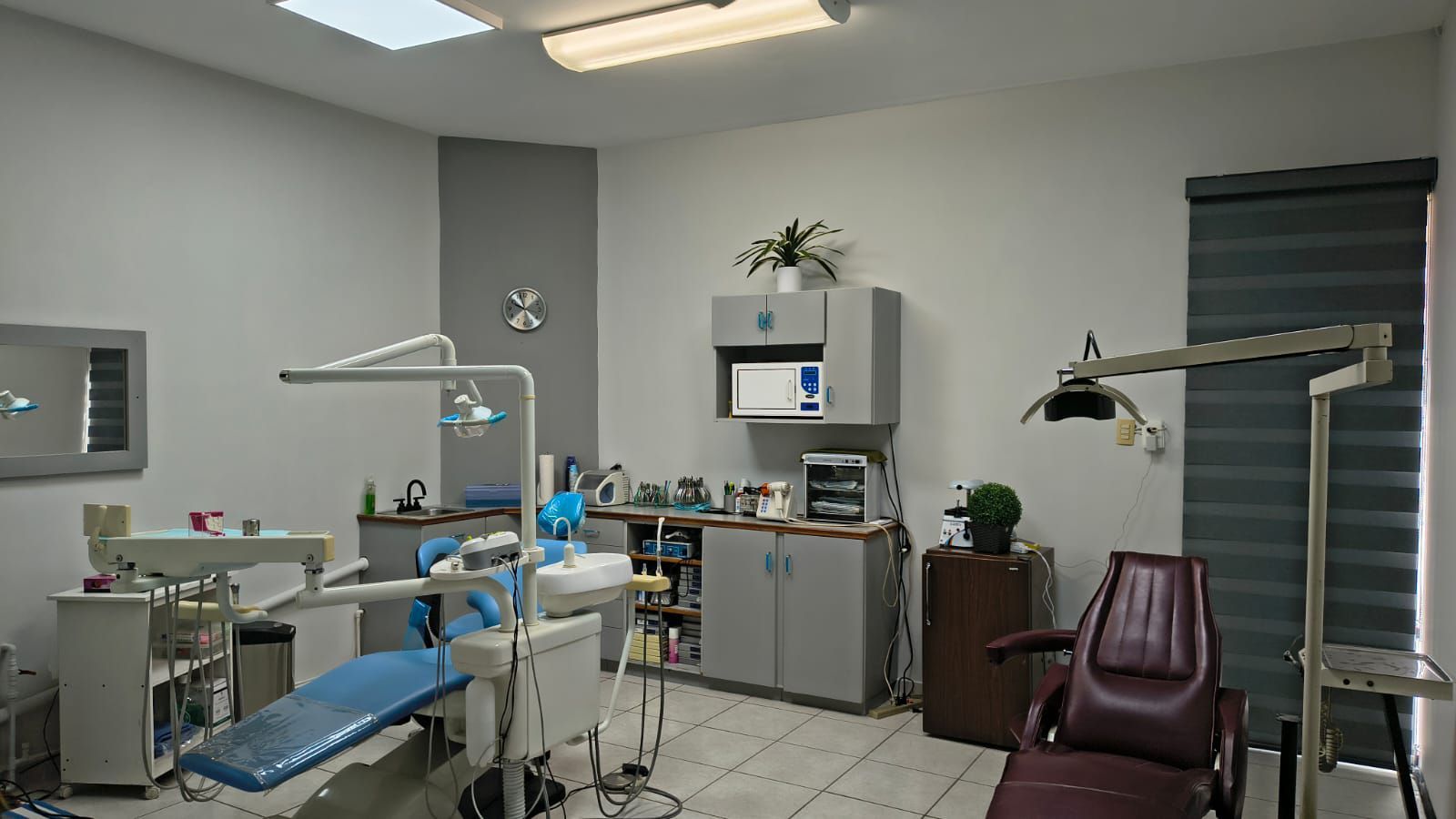 Un consultorio dental con dos sillones para pacientes, gabinetes médicos y equipo dental en una habitación bien iluminada.