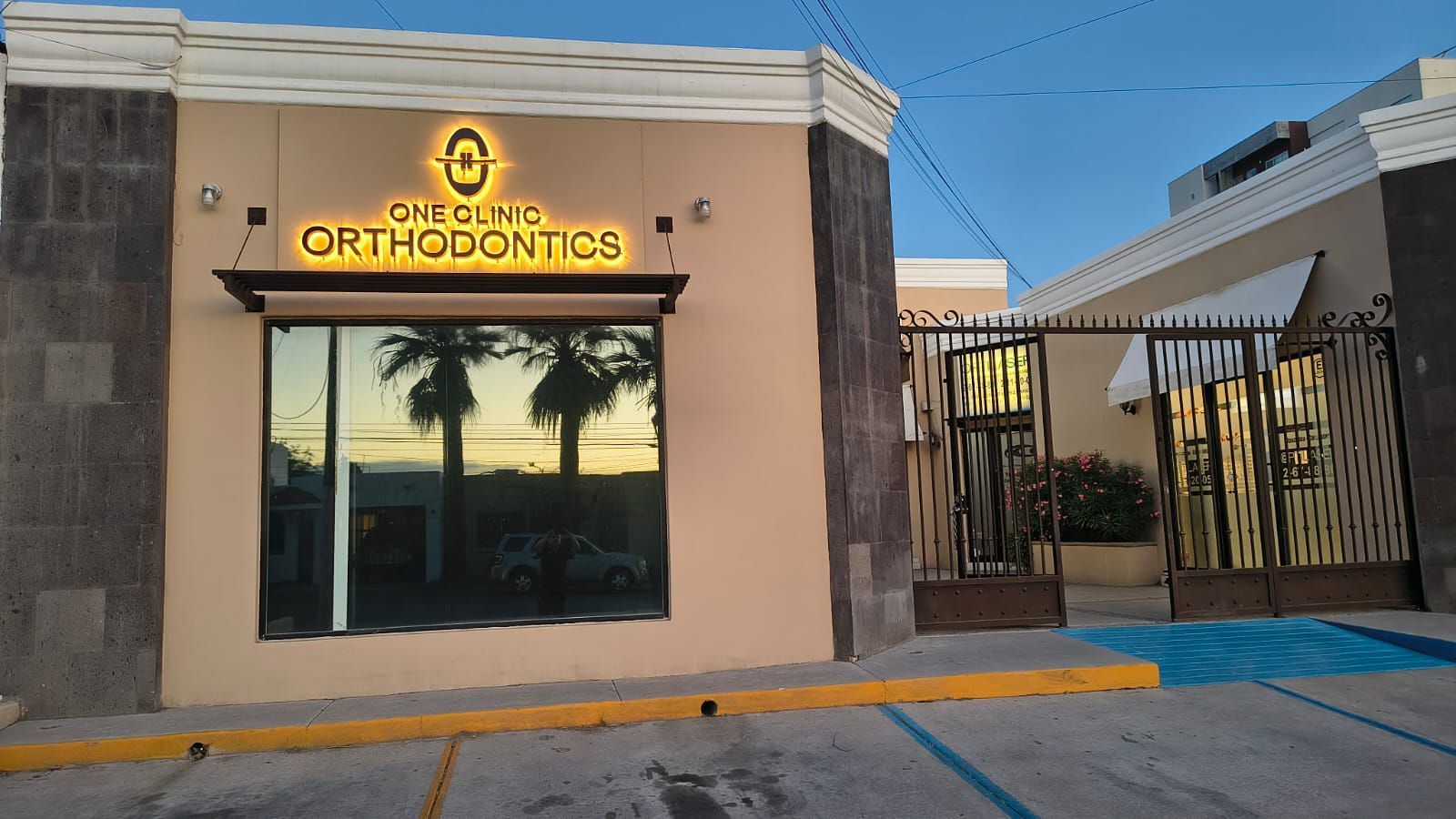 Vista exterior de la fachada de un edificio de color beige con un letrero iluminado de 