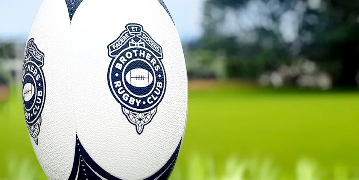 A rugby ball on a pitch at Brothers Rugby Club — the ball has the Brothers logo on the ball.