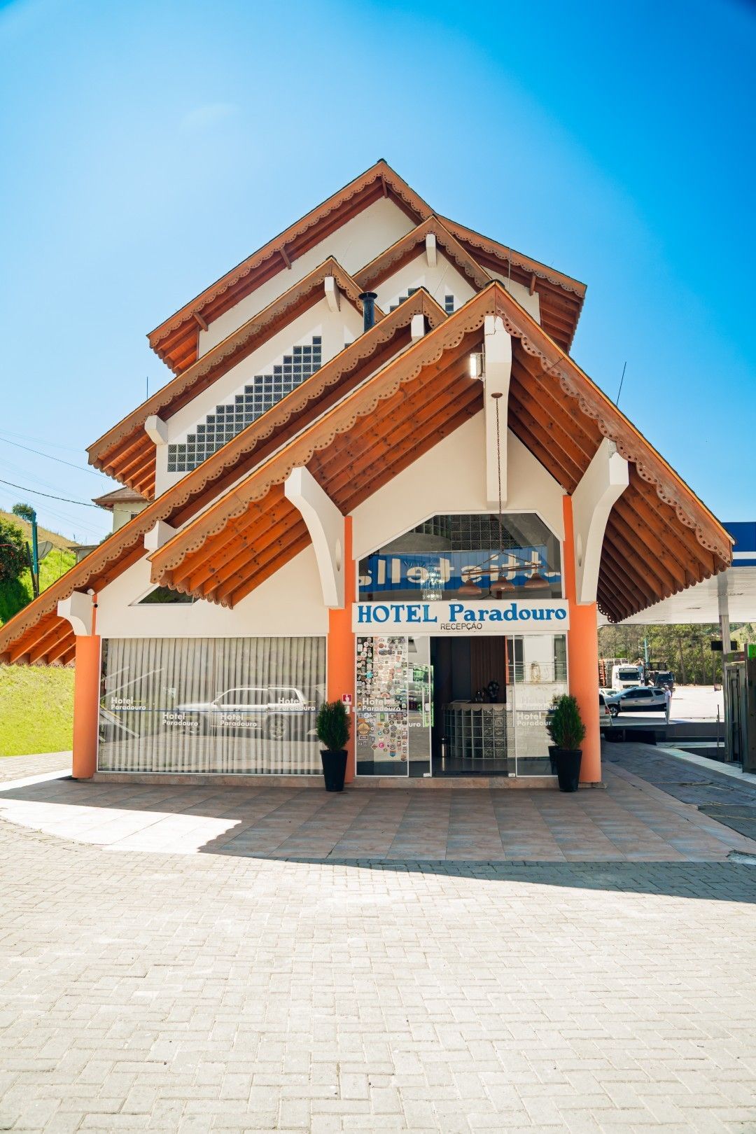 Edifício do Hotel Paradoro com telhado em camadas e detalhes em laranja, céu azul brilhante ao fundo.