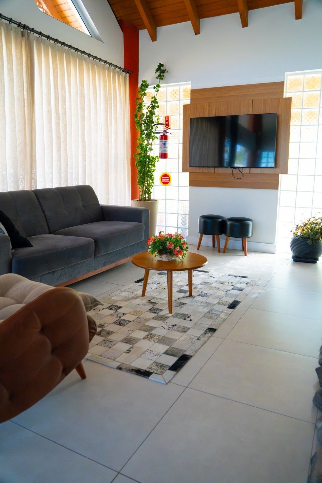 Sala de estar com sofá cinza, TV, mesa de centro redonda e tapete estampado.