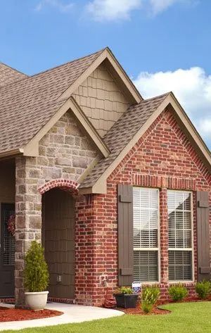 A brick house with a brown roof and shutters