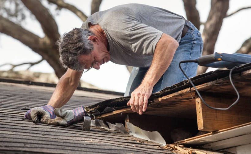 A man is working on the roof of a house. A man is working on the roof of a house.