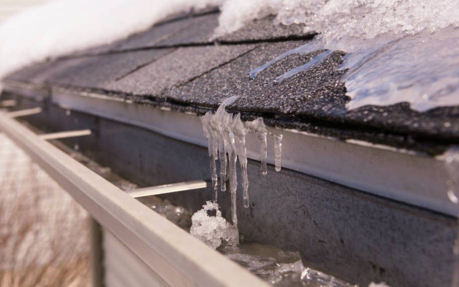 Icicles are hanging from a gutter on a roof. Icicles are hanging from a gutter on a roof.