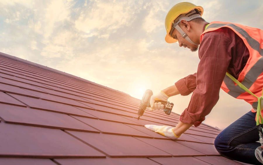 A man is working on a roof with a drill. A man is working on a roof with a drill.
