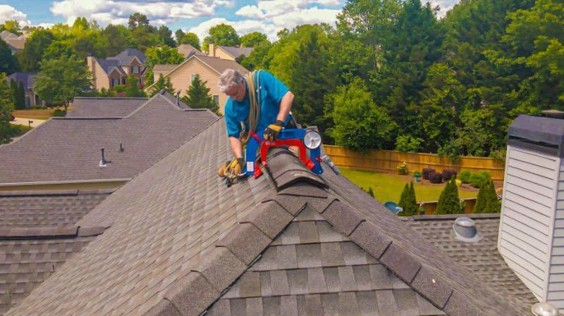 A man is working on the roof of a house. A man is working on the roof of a house.